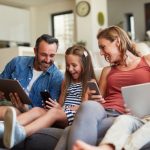 Shot of a happy young family using wireless devices on the sofa at home